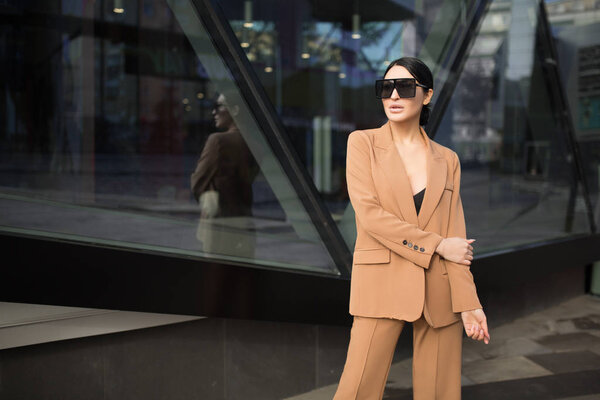 Fashion woman in a business suit and glasses. Standing near a glass building