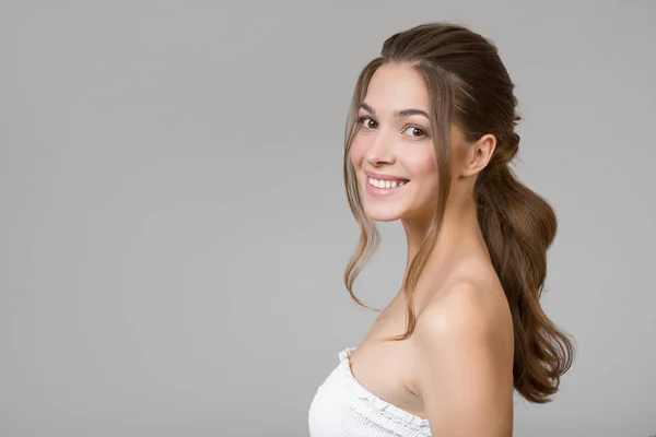 Güzel bir kadının portresi. Gri arka planda güzel bir gülümseme