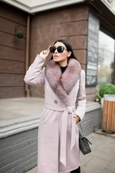 Moda kadını şehirde dolaşıyor. Üzerinde kürk olan bir palto. Ayarla 