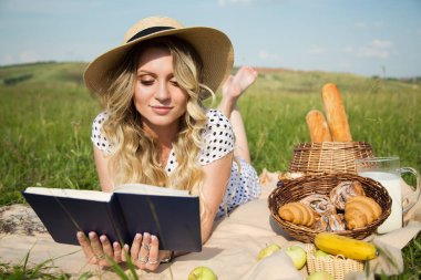 Çayırdaki kadın kitap okuyor. piknik, kırsal bölge. süt ve fırın ürünleri
