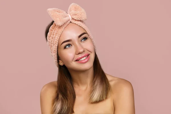 Saçında fiyonk olan zeki bir kadın. Pembe arka planda gülümsüyor. Güzellik. Kopyalama alanı