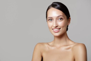 Temiz tenli güzel bir esmer. Yüz ve vücut bakımı. Gri arkaplan