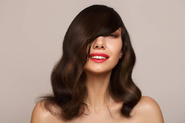 портрет милой улыбающейся брюнетки на сером фоне. Копикапаза