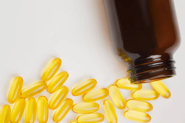 Omega-3 balık yağı kapsülleri şişeden dökülüyor. Vitaminler ve besin takviyeleri