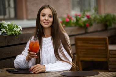 Bir kafede genç ve güzel bir kadın meşrubat içiyor. Kopyala