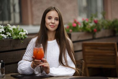 Kafede elinde meşrubat tutan genç ve güzel bir kadın. Kopyala