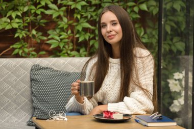 Kafede bir fincan kahve ve peynirli kekle şık bir kadın. İş yemeği.