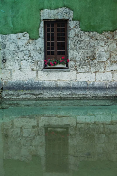 Vieille fenêtre avec des fleurs et le reflet de fenêtre dans l'eau — Photo