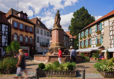 Bulanık turistler Ribeauville 'deki Picturesque caddesini keşfediyorlar.