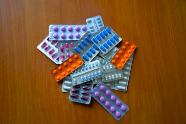 Su toplamış bir sürü hap. Çok renkli haplarla dolu su toplayıcı paketleri. Ahşap arkaplanı kapatın. Tam renkli haplar. İlaç olarak su topladı. Haplı bir paket hap..