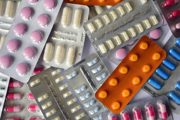 Su toplamış bir sürü hap. Çok renkli haplarla dolu su toplayıcı paketleri. Işık arkaplanına yakın plan. Tam renkli haplar. İlaç olarak su topladı. Haplı bir paket hap..
