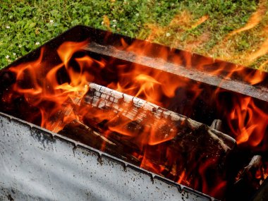 Barbekü ızgarasında odun yakmak. Ateş açın. Açık havada yemek yapmak..