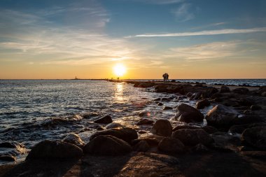 Denizde altın güneş ışınlarıyla renklendirilmiş gün batımı. Rıhtımı ve körfezi görün..