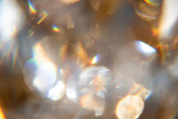 Gökkuşağı ışınlı altın çerçevedeki şeffaf mücevherin soyut bokeh etkisi arka planı.