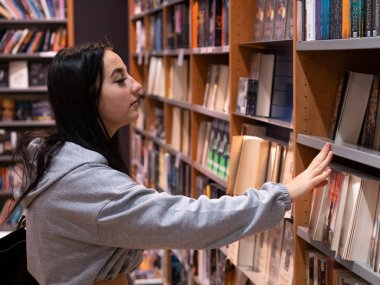 Genç bir kız öğrenci bir kitapt yeni bir ders kitabı arıyor