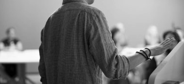 İş eğitmeni bir grup insana sunum yapıyor. Liderlik koçu uluslararası forum sırasında konferans salonunda yönetim öğrencilerine brifing veriyor. Sunucu girişimcilere ders veriyor. 