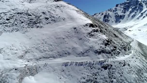 Luftaufnahme. Gruppe von Menschen, die auf den verschneiten Berg gehen. Drohne schießt von oben — Stockvideo
