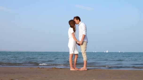 Молодая пара целуется на солнечном пляже — стоковое видео