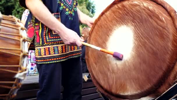 Az ember játszik Dobverővel az afrikai djembe tehenek bőrén. Utcai zárás — Stock videók