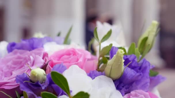 Свадебный букет острый на переднем плане с невестой и женихом на мягком фоне фокуса — стоковое видео
