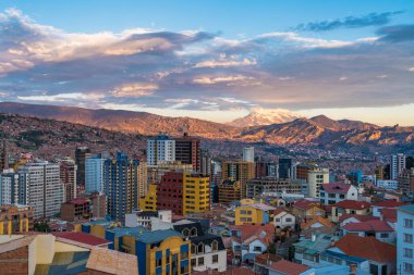 Aerial view of La Paz cityscape including Illimani mountain and residential buildings at sunset in Bolivia, South America. clipart