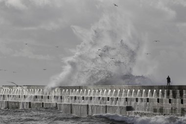 Porto, Portekiz - 2 Ocak 2016: Portekiz kuzeyden bir iskelede büyük fırtınalı deniz dalgaları seyretmekten adam