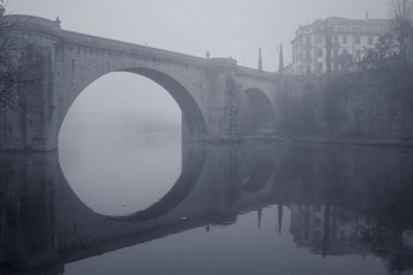 Tarihi köprü, Amarante (Portekiz) soğuk ve Sisli sabah. Romantik Tamega Nehri. Tonda mavi.