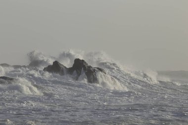 Büyük dalga Kuzey Portekiz kıyısında kayalardan kapsayan.