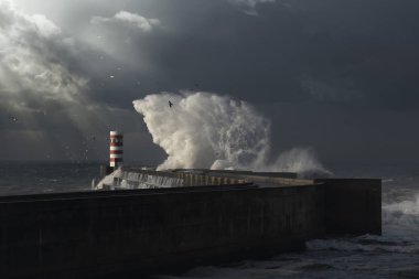 Douro nehir ağzı güneş ışınları ve büyük deniz dalga splash iskele ve işaret, Porto, Portekiz ile karanlık fırtınalı gün.