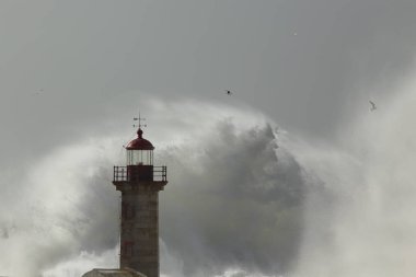 Fırtınalı denizde dalga sıçrama ve sprey. Yumuşak arkadan aydınlatmalı. Oporto eski deniz feneri.