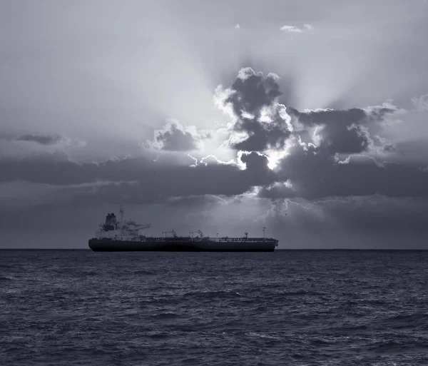 日落时停靠在海岸外的小型油轮 转换为黑色和白色 — 图库照片