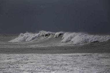 Portekiz kıyısında yağmur ve fırtına büyük beyaz dalgalar sahile yaklaşırken görme önce.