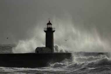 Eski deniz feneri ve iskelesi ulaştıktan sonra büyük bir dalga sprey. Yumuşak arkadan aydınlatmalı. Douro nehir ağzı fırtınalı bir günde, Porto, Portekiz.