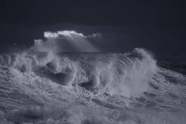 Gün batımında karanlık gökyüzüne karşı fırtınalı dalgalar