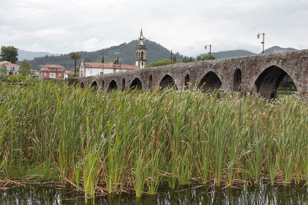 Old granite bridge and church from the medieval city of Ponte de Lima in a rainy day. Northern portuguese way to Santiago de Compostela.
