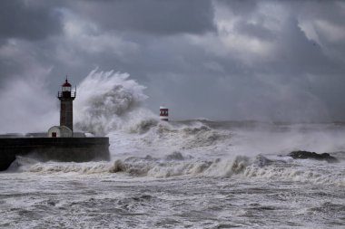 Fırtınalı karanlık bulutlu gökyüzüne karşı büyük beyaz dalgalar ve deniz feneri. Douro nehri ağzı, Porto, Portekiz.
