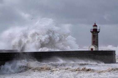 Büyük fırtınalı deniz dalgaları iskele ve eski deniz feneri üzerinden sıçrıyor, Portekiz