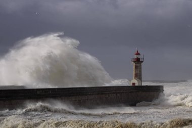 Büyük deniz dalgası sıçrıyor ve püskürtüyor. Oporto eski deniz feneri.
