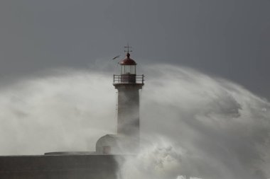 Büyük deniz dalgası sıçrıyor ve püskürtüyor. Oporto eski deniz feneri.