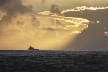 Gün batımında güzel deniz manzarası ufukta bir petrol tankeri görüyor.