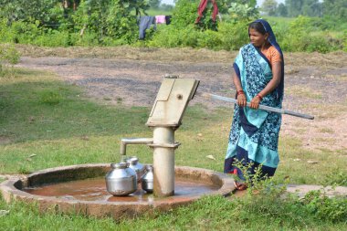 TIKAMGARH, MADHYA PRADESH, Hindistan - 14 Eylül 2020: Kimliği belirsiz Hintli kadın içme suyu pompası kullanıyor.