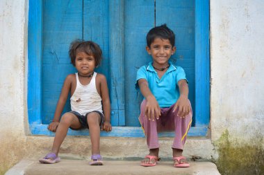 TIKAMGARH, MADHYA PRADESH, Hindistan - 14 Eylül 2020: Kimliği belirsiz bir erkek ve bir kız evlerinin kapısında oturuyorlar.