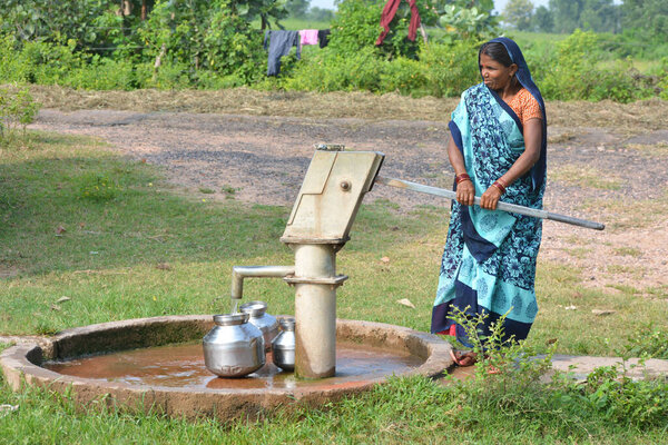 TIKAMGARH, MADHYA PRADESH, INDIA - 14 СЕНТЯБРЯ 2020: Неизвестная индийская женщина использует ручной насос для питьевой воды.