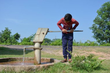 TIKAMGARH, MADHYA PRADESH, İNDİYA - 15 Eylül 2020: Kimliği belirsiz Hintli köylü çocuk el pompası yapıyor.