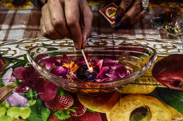 A indian lady lit up a jar is which is loaded with rose and cand