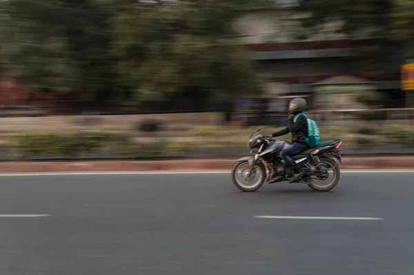 Panning technique of biker who is going for some work at evening on the road — Stock Photo, Image