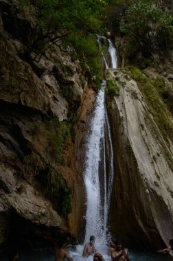 Ünlü Neer Garh Şelalesi, Rishikesh, Uttarakhand, Hindistan 'ın altında eğlenen bir grup insan.