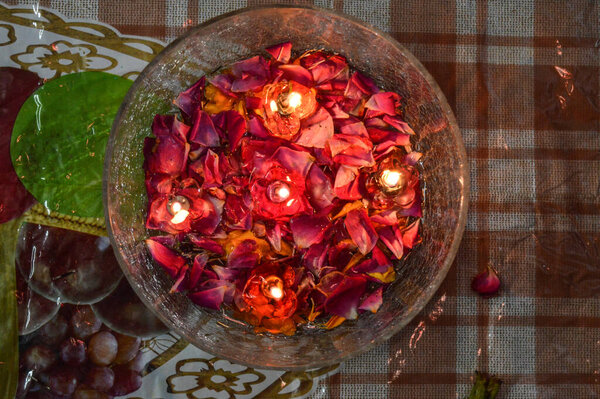 A jar is which is loaded with rose and candle on indian festival diwali deepawali with fire isolated on table