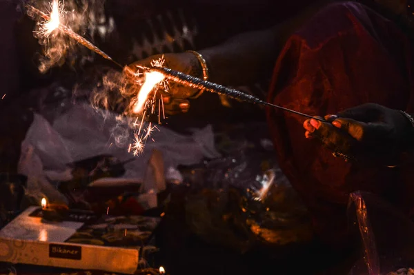 Hint bayan ateş krakeriyle oynayan gül ve mumla Hint festivali diwali deep awali 'de masada izole edilmiş ateşle