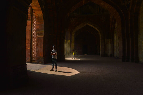 Индийский мальчик дает позу для моды съемки внутри старого форта и сотрудник ASI очистки области.